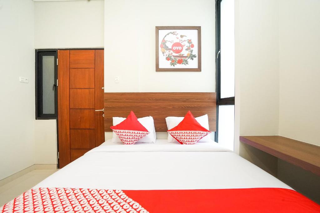 una camera da letto con un letto con cuscini rossi e bianchi di Super OYO Capital O 449 The Colins a Keputih