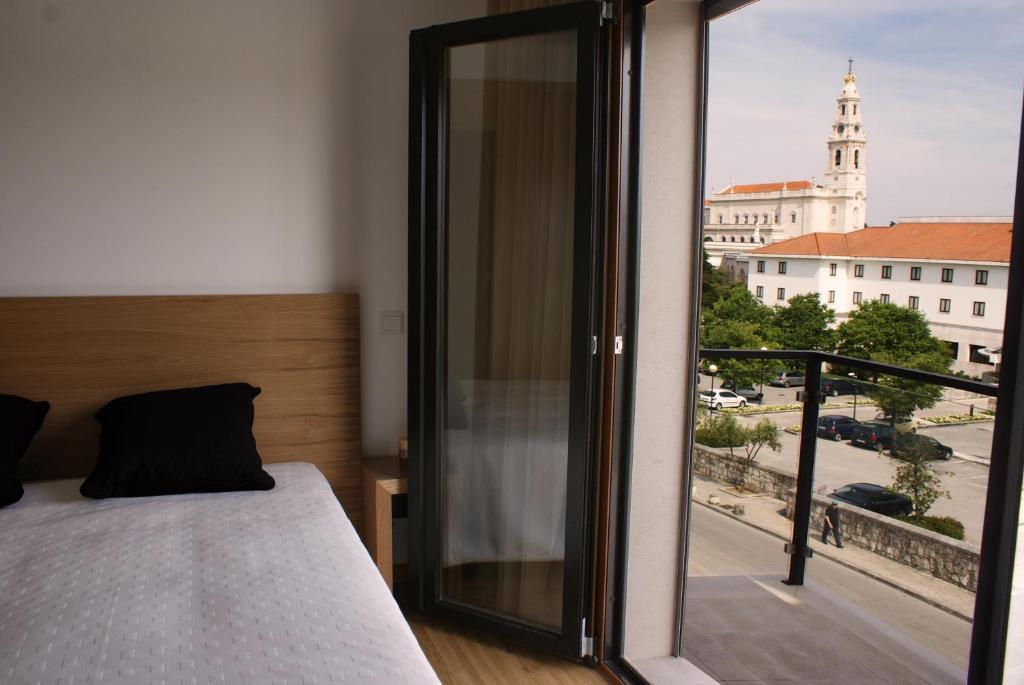 a bedroom with a bed and a balcony with a view at Santa Noite in Fátima