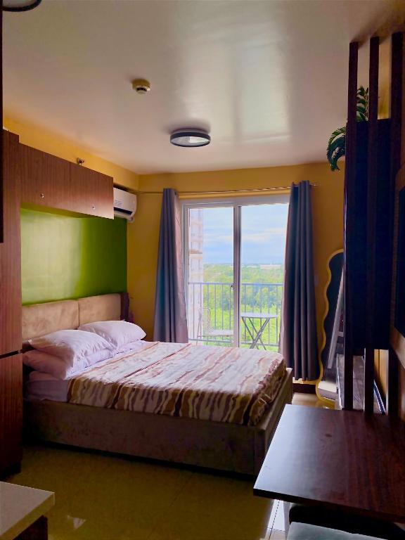 a bedroom with a bed and a large window at Timbi Suites Mactan in Lapu Lapu City