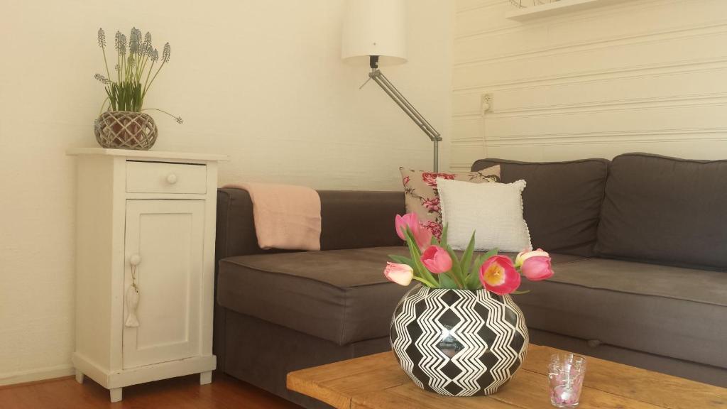 ein Wohnzimmer mit einem Sofa und einer Vase mit Blumen in der Unterkunft Apartment Boven Jan 572 in Den Helder