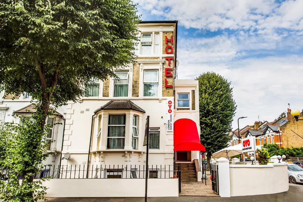 a large white building with a red awning at OYO London Guest House in London