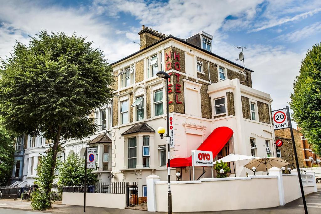 a large white building with a red awning at London Guest House by OYO - Acton in London