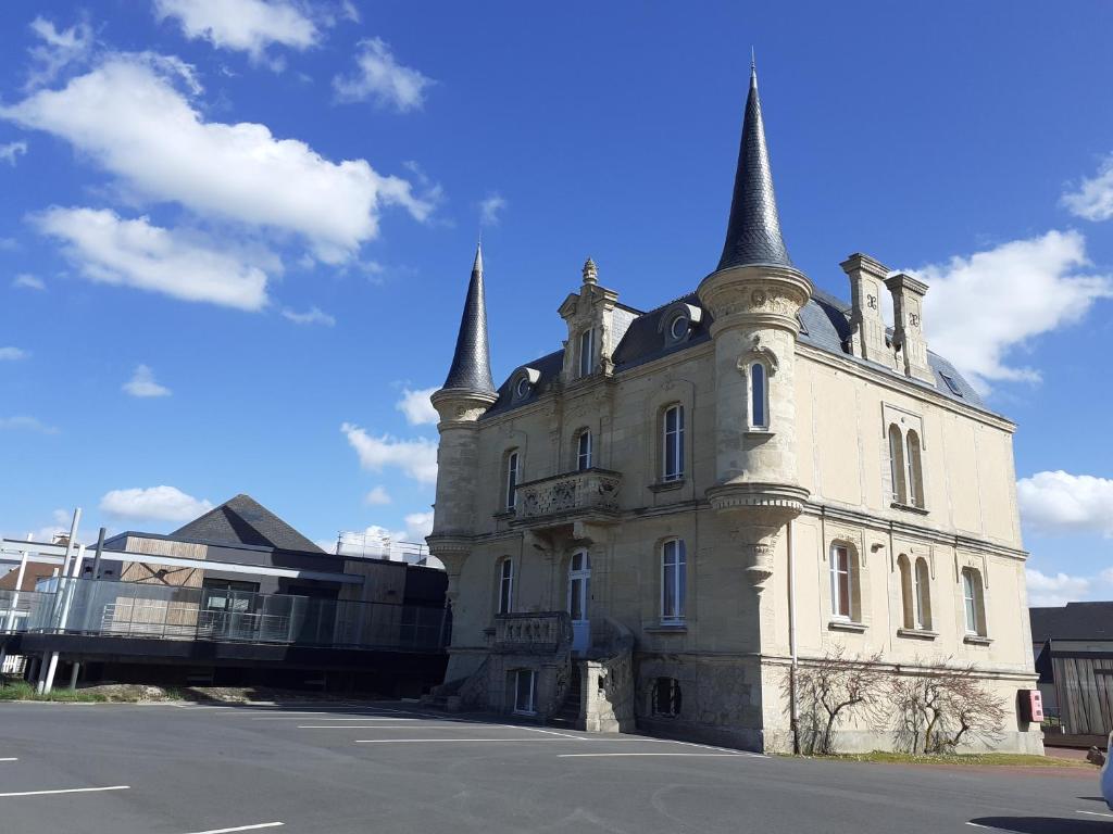 an old building with two towers on a street at Les Tourelles - Chalets & Chambres en Bord de Mer in Asnelles