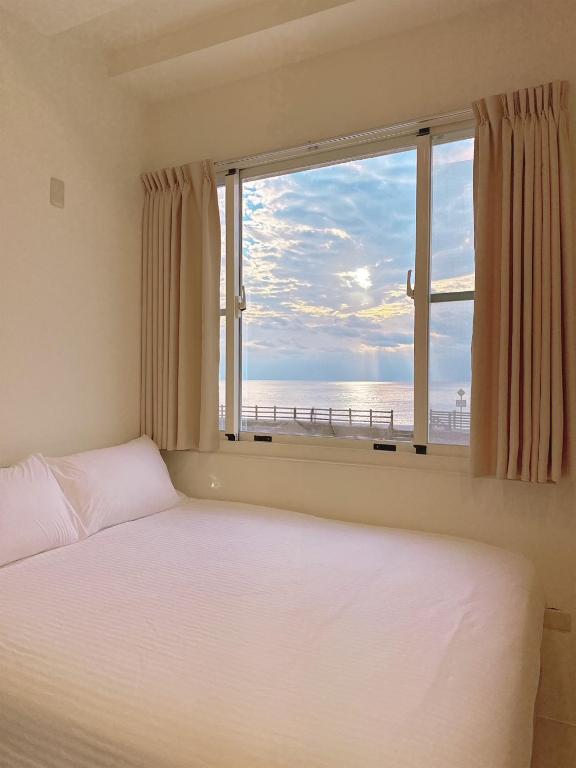una camera da letto con finestra affacciata sull'oceano di MuyuTime B&B a Green Island