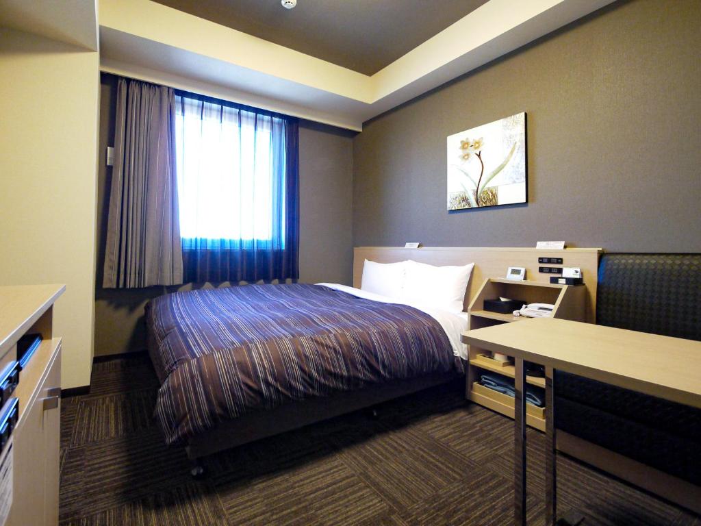 海老名市にあるホテルルートイン海老名駅前のベッドとデスクが備わるホテルルームです。