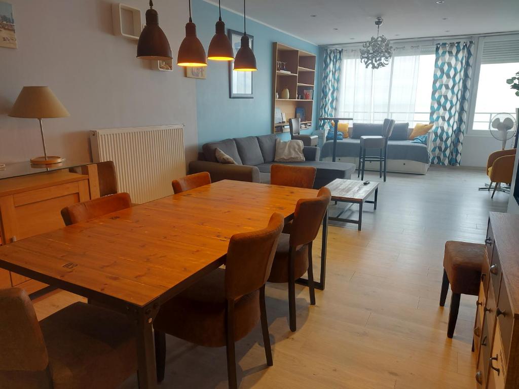 un salon avec une table et des chaises en bois dans l'établissement Appartement de standing bord de plage malo, à Dunkerque