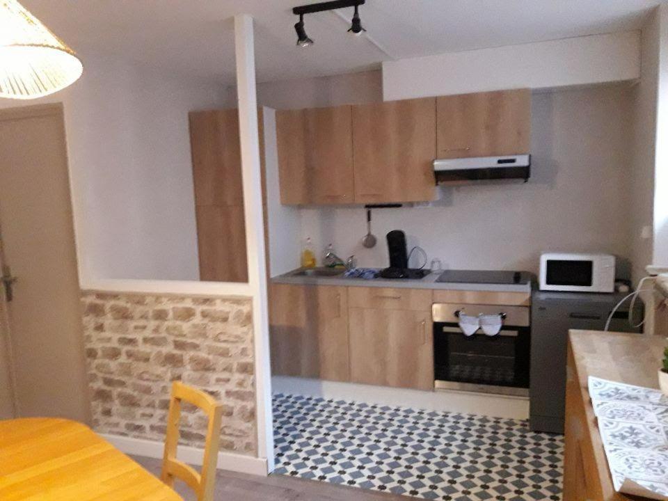 une petite cuisine avec une cuisinière et un micro-ondes dans l'établissement Appartement , 500 m de la mer, à Le Portel