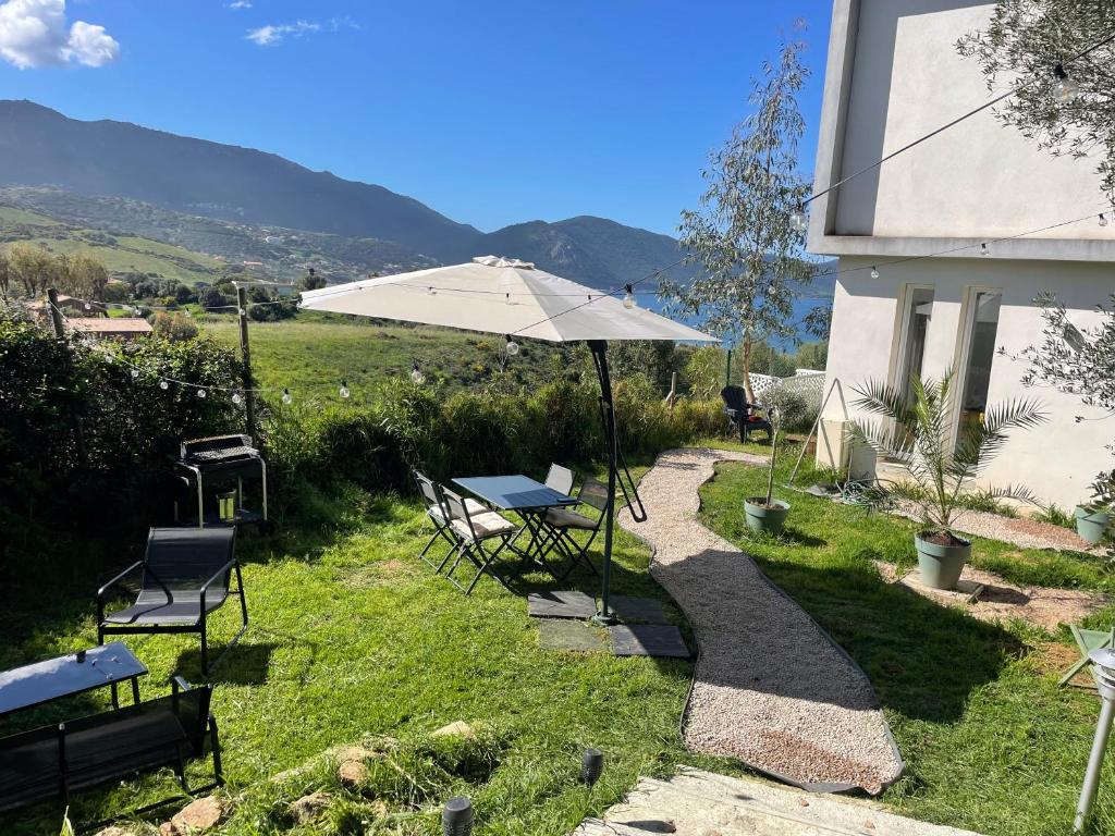 une table et des chaises avec un parasol dans l'herbe dans l'établissement Rez de villa golfe de lava, à Appietto
