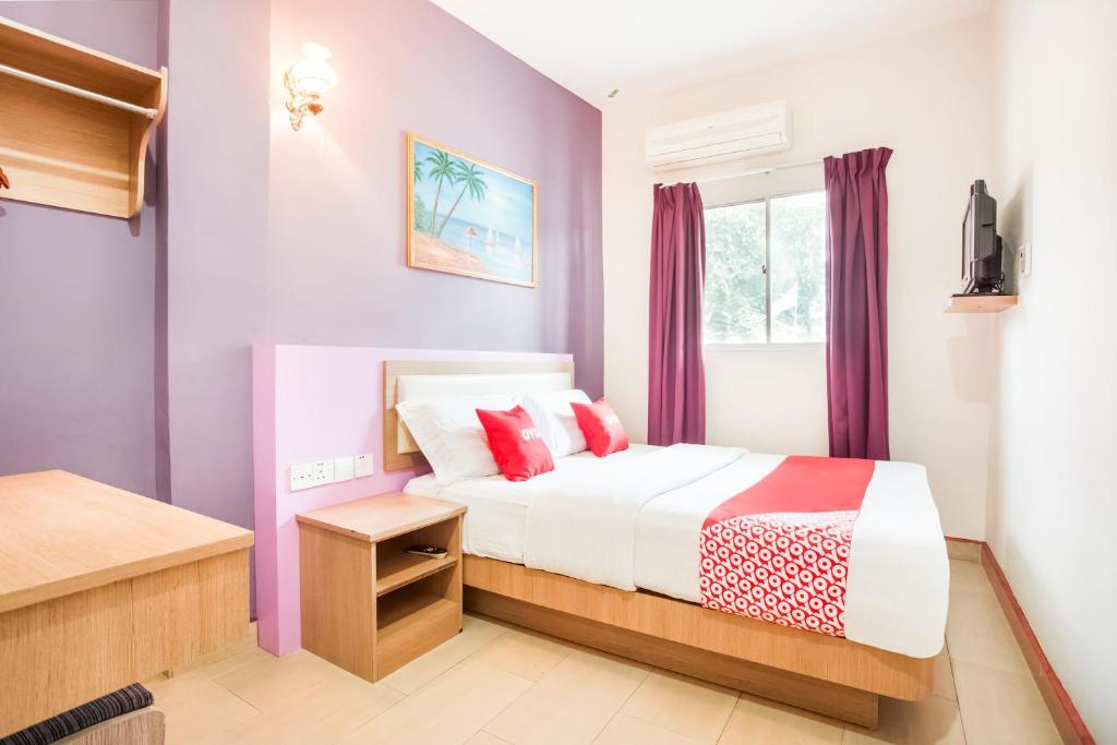 a bedroom with purple walls and a bed with red pillows at Valley View Hotel in Lumut