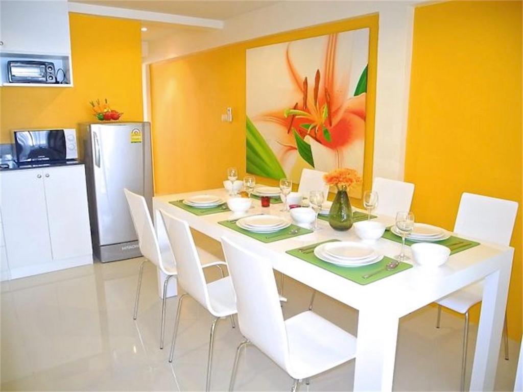 a dining room with a white table and white chairs at Kata Plaza 1 bedroom Modern Apartment in Kata Beach