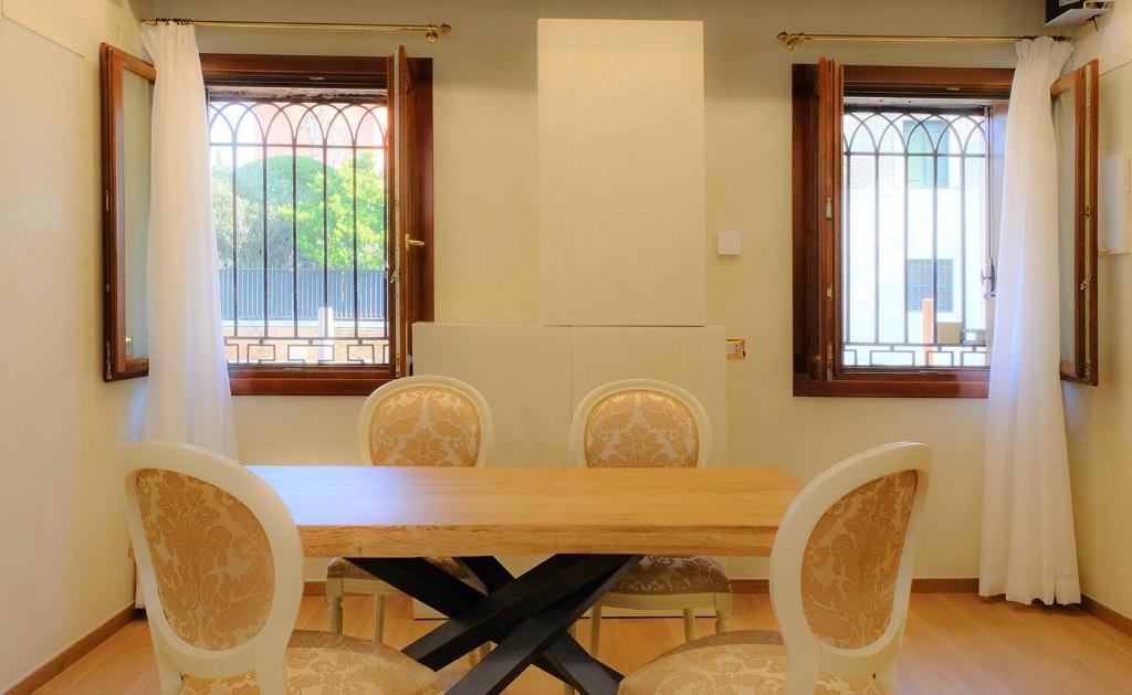 Hotel Vista Canale, a dining room table with chairs and two windows at Vista Canale in Venice