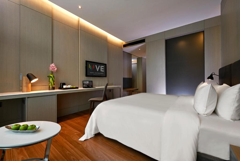 A modern guest room combines a white bed with a built-in desk.