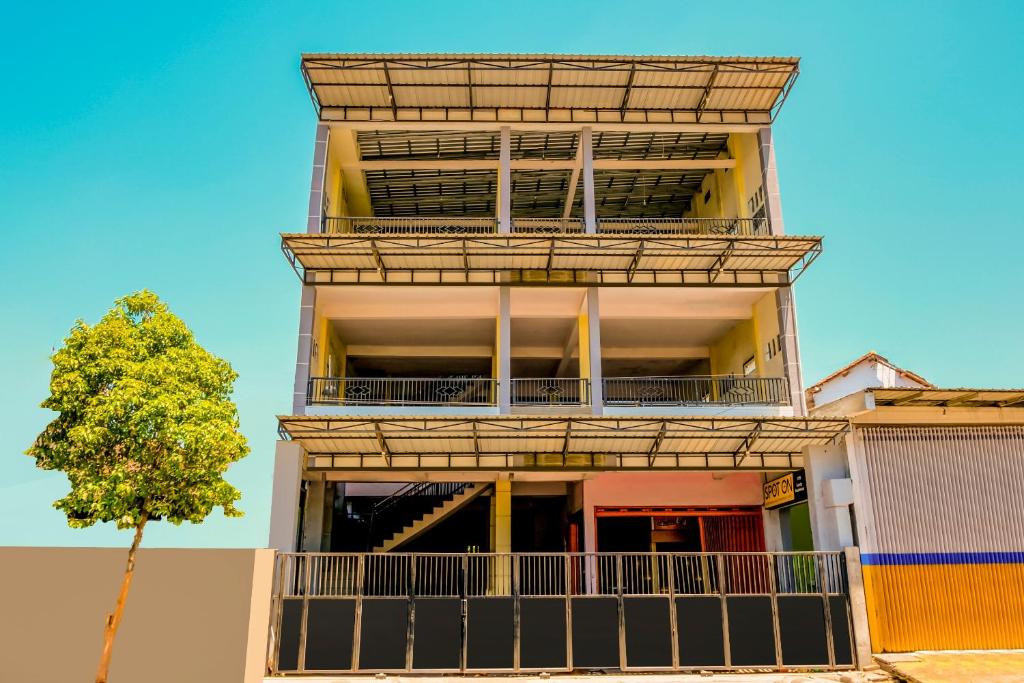 un edificio alto con balcones y un árbol en Hotel O Family Residence Syariah, en Kediri