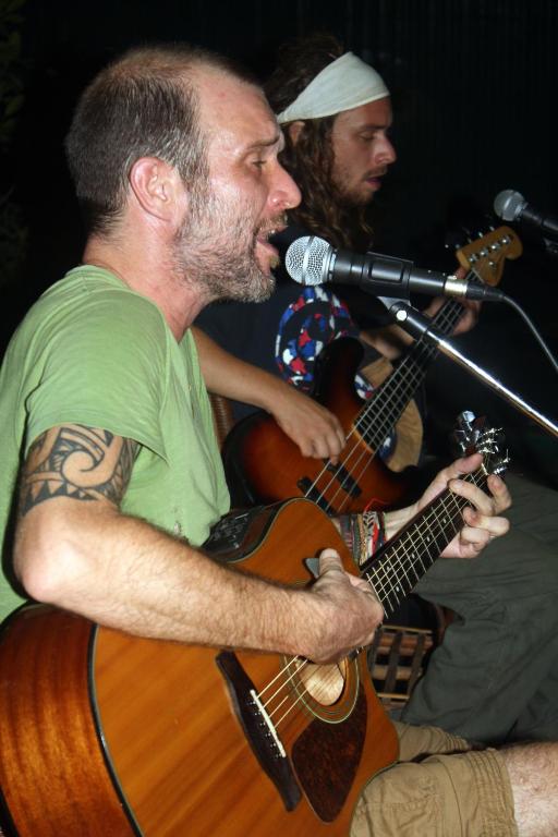a man playing a guitar with a microphone at The Magic Sponge in Kampot