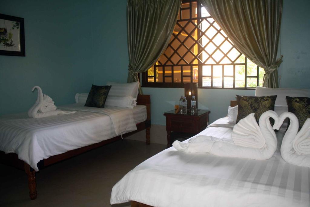 a bedroom with two beds with swans made out of towels at The Magic Sponge in Kampot