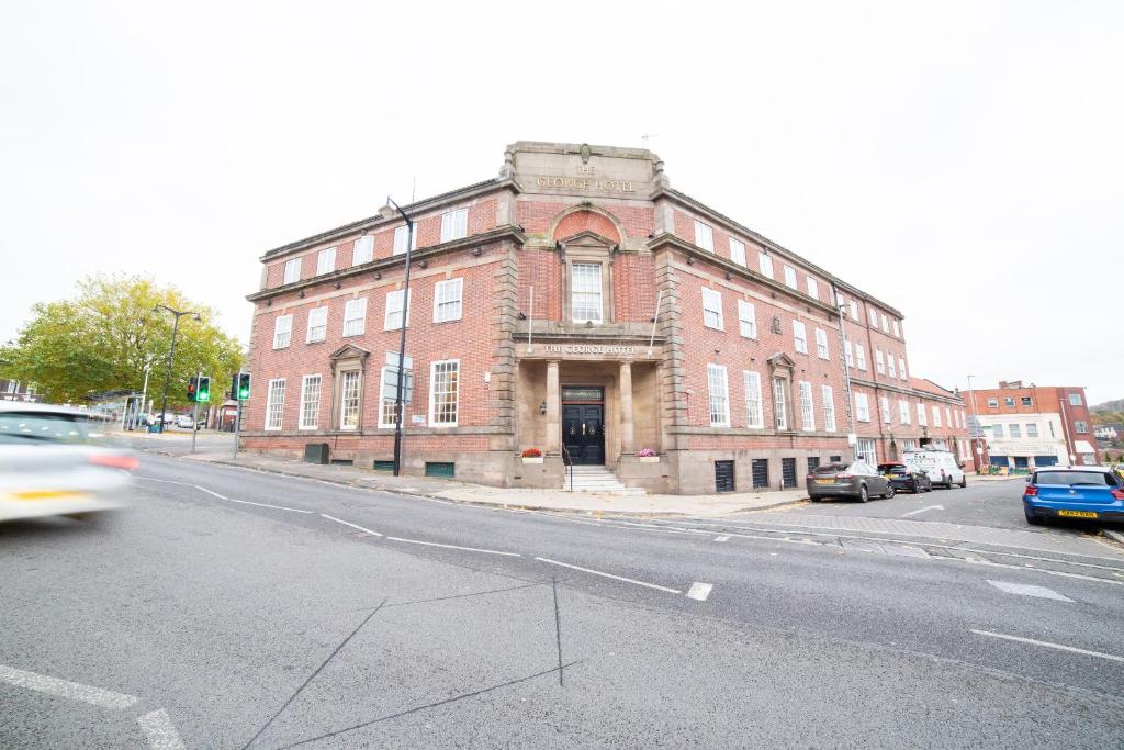 an old red brick building on a city street at George Hotel, Burslem, Stoke-on-Trent in Stoke on Trent