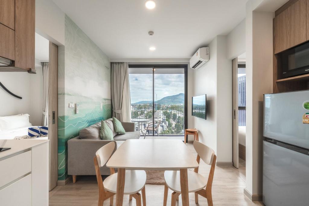 a kitchen and a living room with a table and chairs at Laguna Skypark Apartments by Stayisle in Thalang