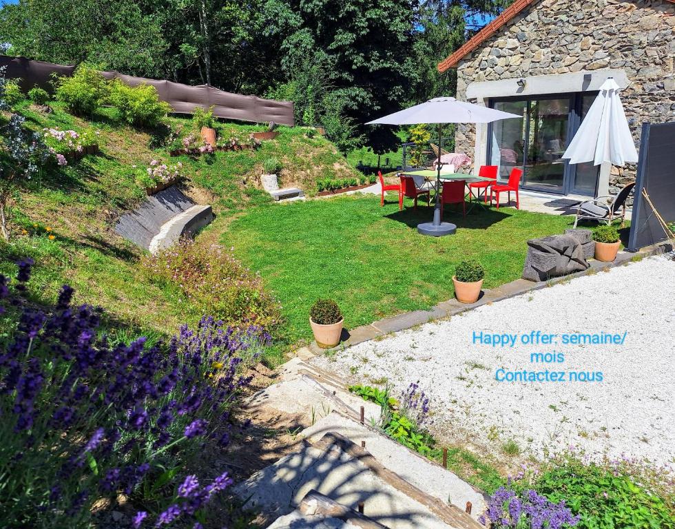 un jardin avec une table et un parasol dans l'établissement Grand cottage le pré bleu 11mn lac, à Thizy-les-Bourgs