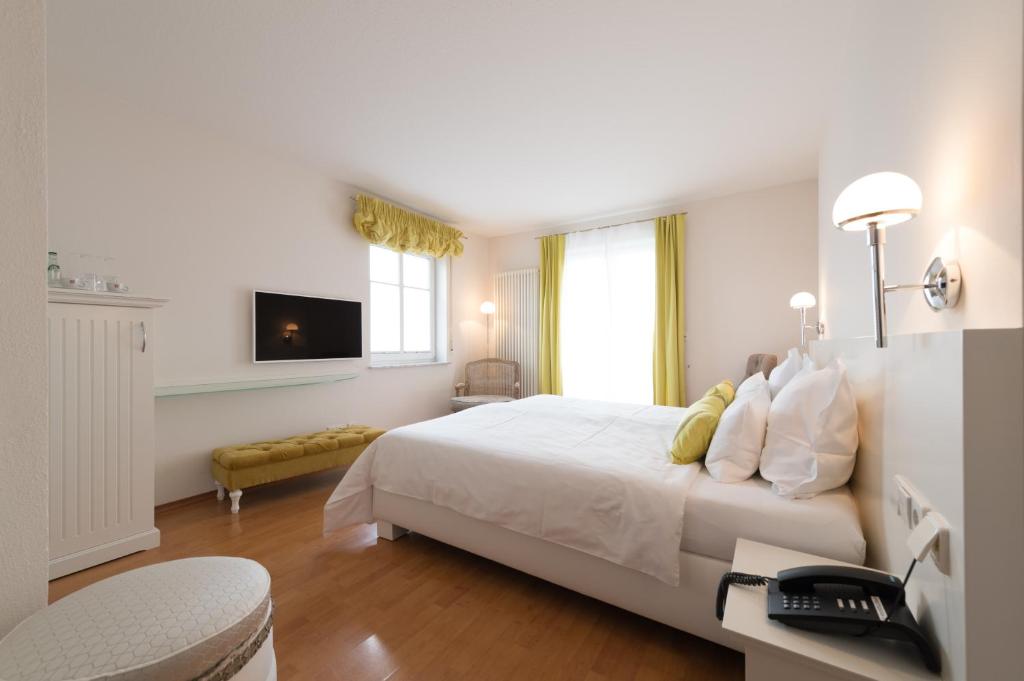 een witte slaapkamer met een bed en een televisie bij Hotel Villa Seeschau - Adults only in Meersburg