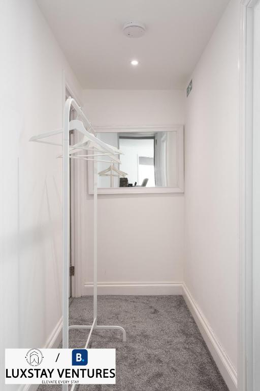 a white room with a white shelf and a mirror at Bright and Spacious 2BR Maisonette Sleeps 8, Game Room, 5 mins to Brighton Beach and City Centre in Brighton & Hove