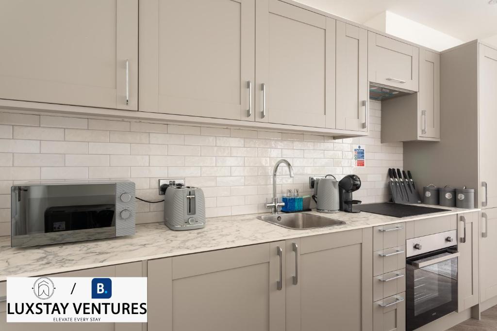 a kitchen with white cabinets and a sink and a microwave at Bright and Spacious 2BR Maisonette Sleeps 8, Game Room, 5 mins to Brighton Beach and City Centre in Brighton & Hove