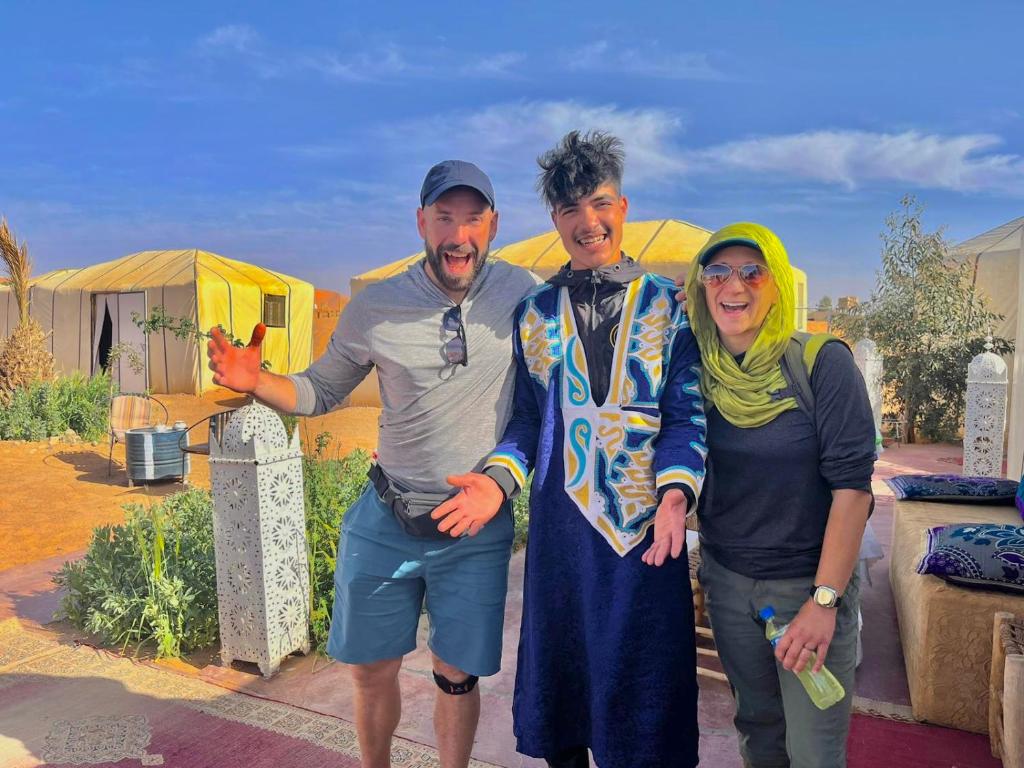 a group of three people posing for a picture at Guesthub camp in Merzouga