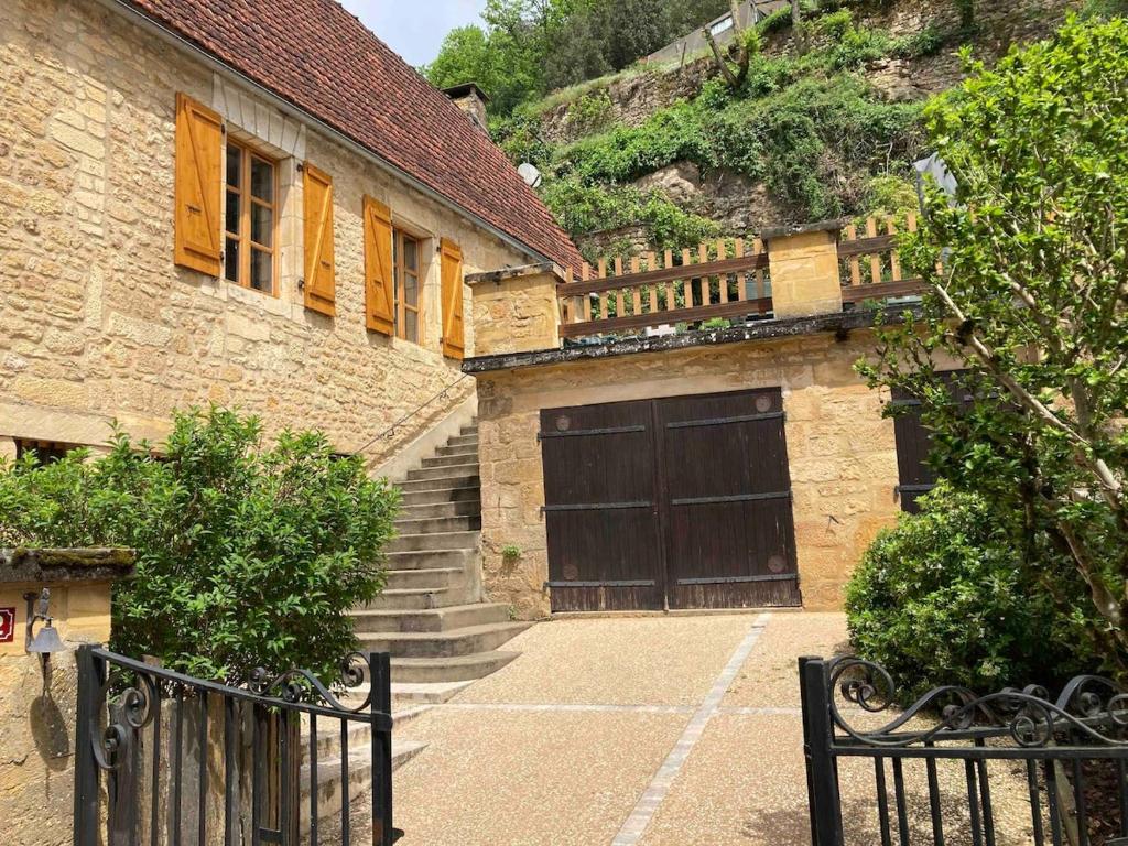 un bâtiment avec un portail et une porte de garage dans l'établissement Les Althéas - Gîte familial avec terrasses - Sarlat, à Groléjac