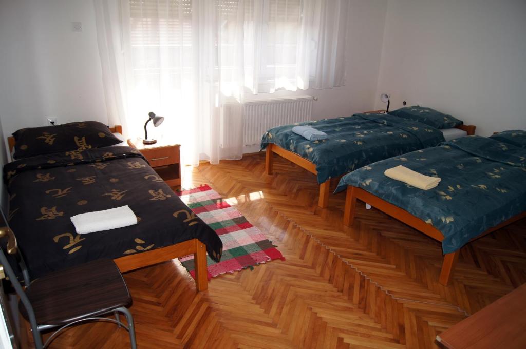 two beds in a room with wooden floors at Guest House Stara Baranja in Kneževi Vinogradi