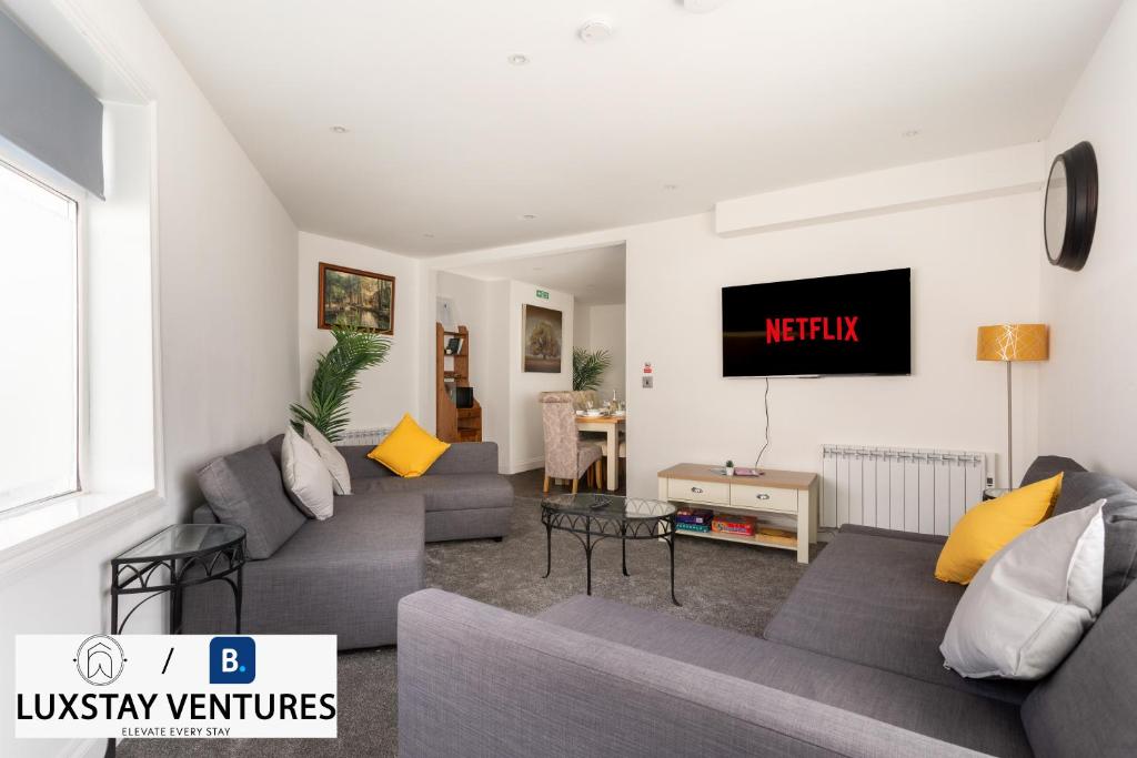 a living room with couches and a tv on the wall at Bright and Spacious 2BR Maisonette Sleeps 8, Game Room, 5 mins to Brighton Beach and City Centre in Brighton & Hove