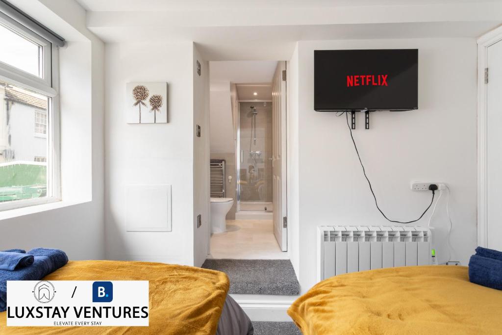 a bedroom with a tv on the wall and a bed at Bright and Spacious 2BR Maisonette Sleeps 8, Game Room, 5 mins to Brighton Beach and City Centre in Brighton & Hove