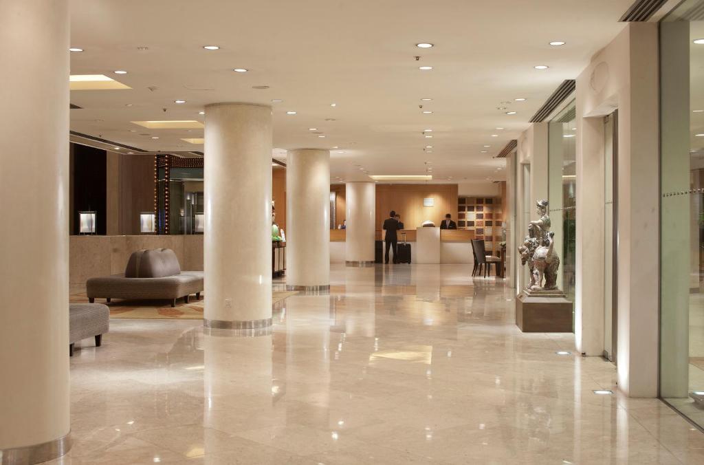 una hall con colonne e divani in un edificio di The Royal Garden a Hong Kong