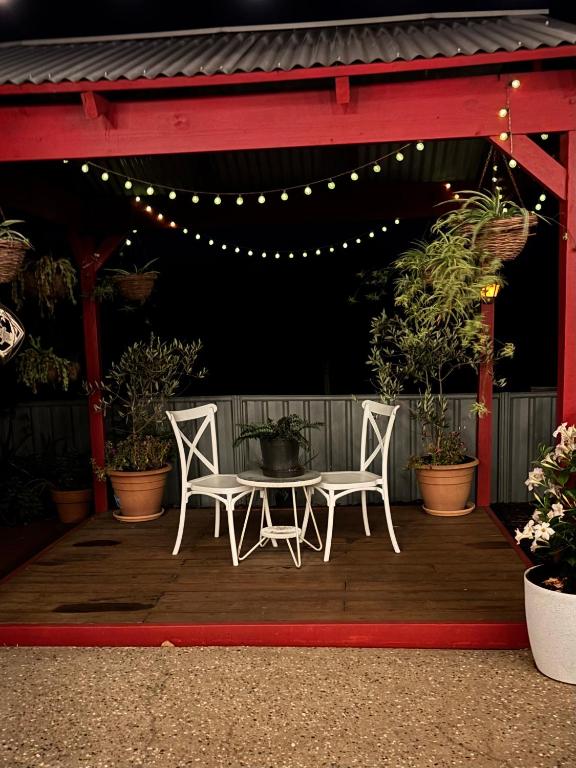 two white chairs and a table on a wooden deck at Sage Cottage in Cowaramup