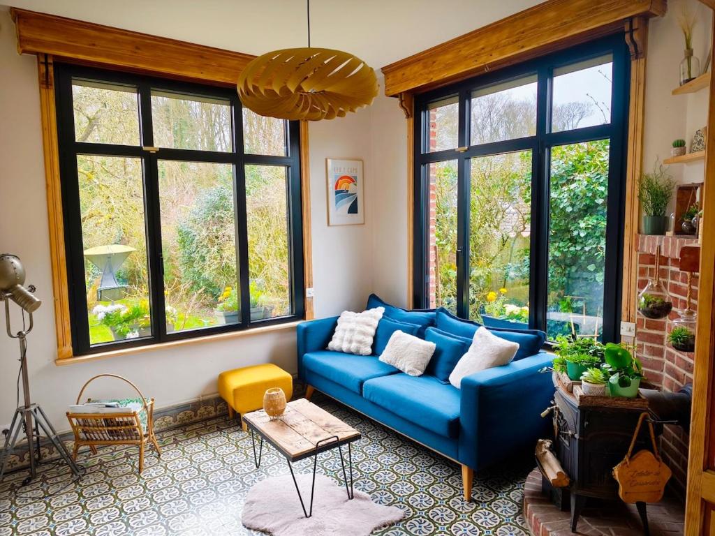 - un canapé bleu dans le salon avec fenêtres dans l'établissement Cassandra's Cottage, à Sebourg