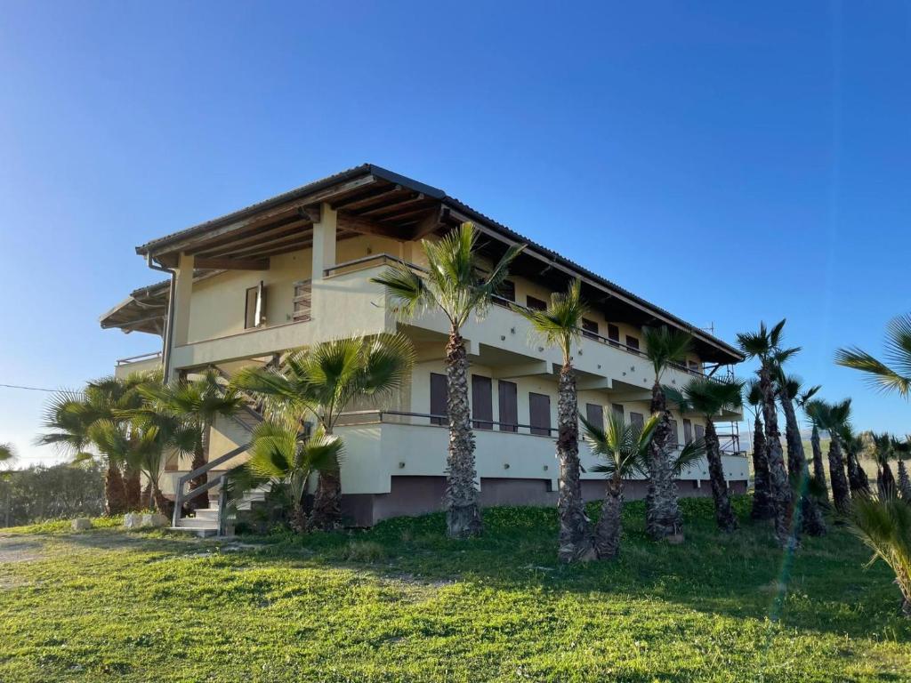 a building with palm trees in front of it at home SIKAN casa al mare Licata in Butera