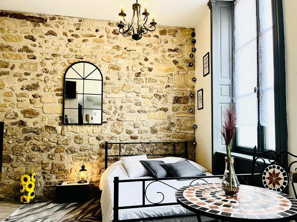une chambre avec un lit et un mur en pierre dans l'établissement capucin 2 super studio au pied de la cathédrale, à Reims
