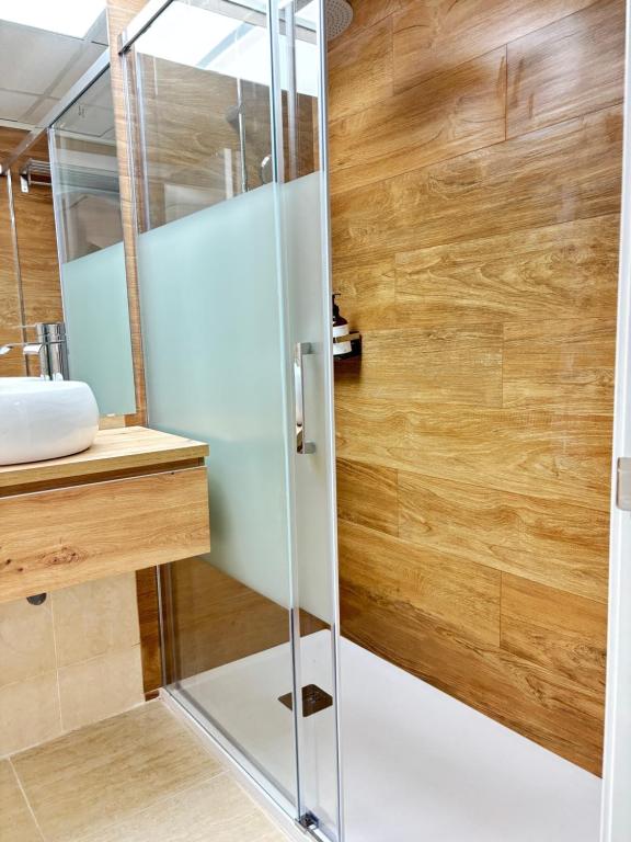 a glass shower in a bathroom with a wooden wall at Ático Calblanque in Mar de Cristal