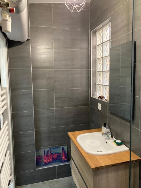 ein Badezimmer mit Waschbecken und Spiegel in der Unterkunft Atelier des lilas in Les Lilas