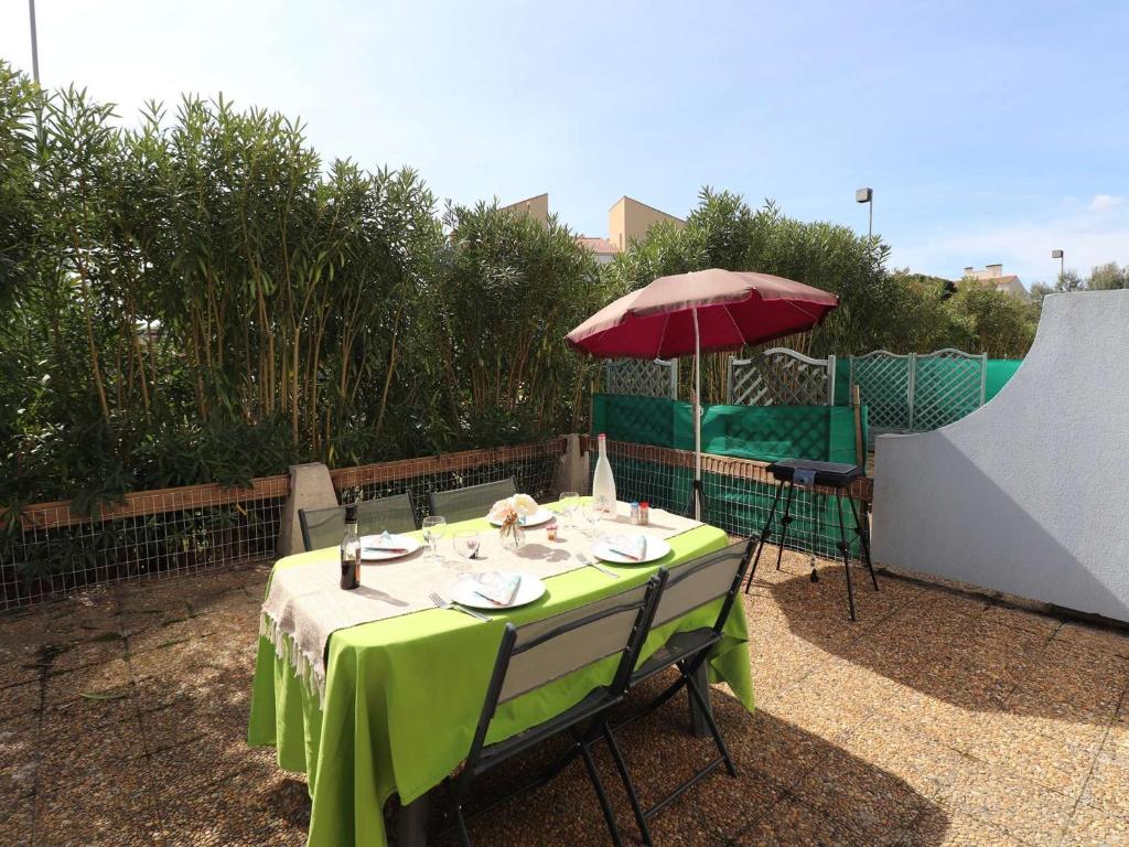 une table avec un tissu de table vert et un parasol dans l'établissement Appartement T2 avec Terrasse et Piscine au Grau-du-Roi, Proche Mer et Commerces - FR-1-307-237, au Grau-du-Roi