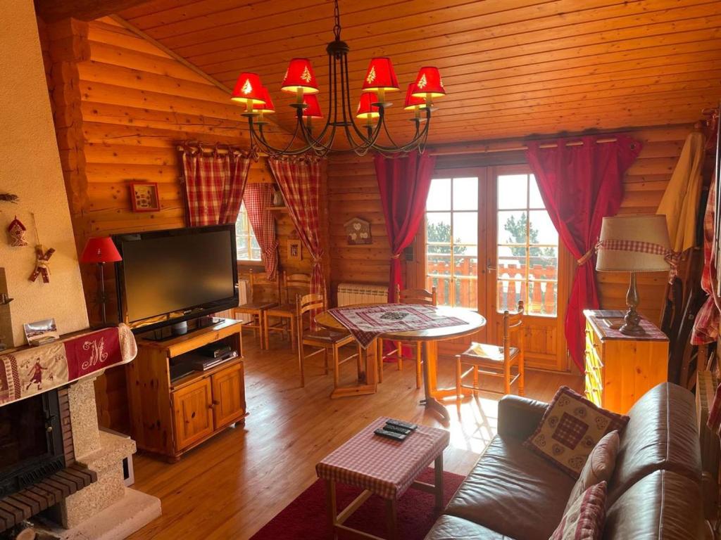 a living room with a couch and a table and a television at Charmant Chalet avec Cheminée et Terrasse aux Angles - FR-1-593-128 in Les Angles