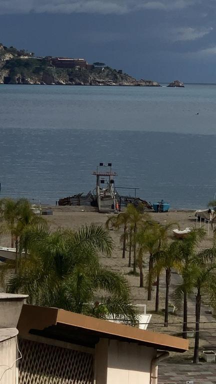 a boat sitting on a beach with palm trees at Home Rosal Schisò Beach in Giardini Naxos