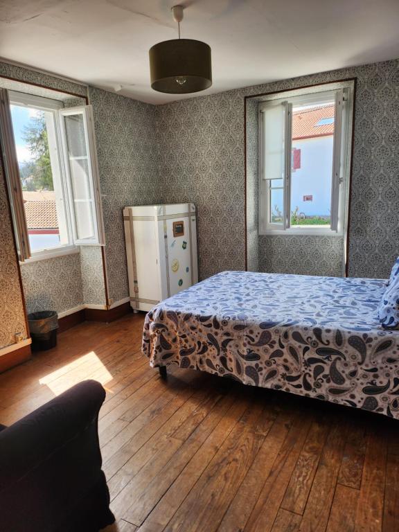 a bedroom with a bed and two windows at Gite Compostella in Saint-Jean-Pied-de-Port