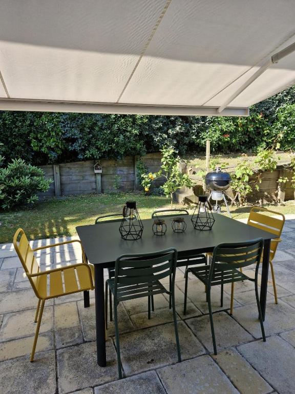 une table et des chaises noires sous un parasol dans l'établissement Holiday home for families close to shops and beach, à Capbreton