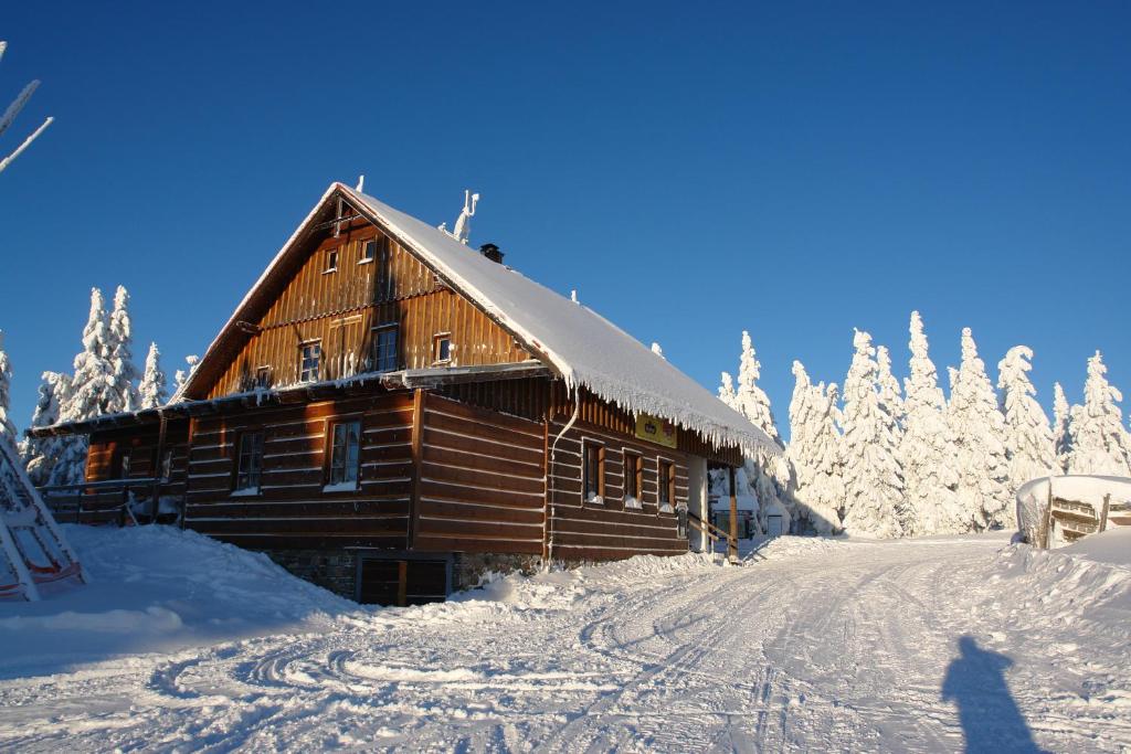 ヤンスケー・ラーズニェにあるKiosek U Staré Lanovkyのスキー場の雪上の丸太小屋