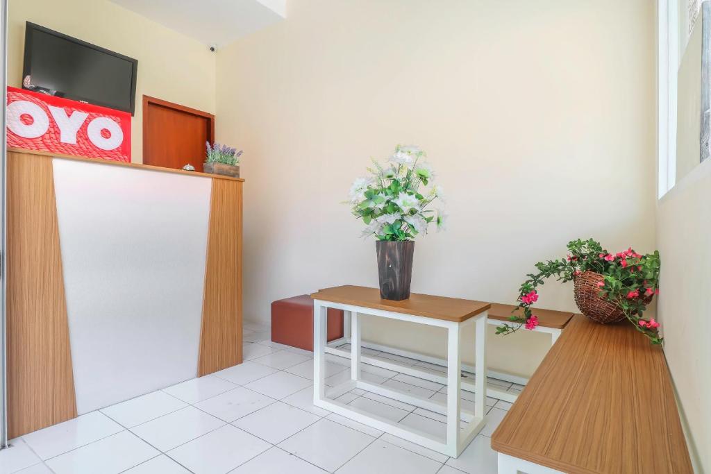 a waiting room with a table with flowers on it at OYO 2184 Nan Berlian Inn in Legian