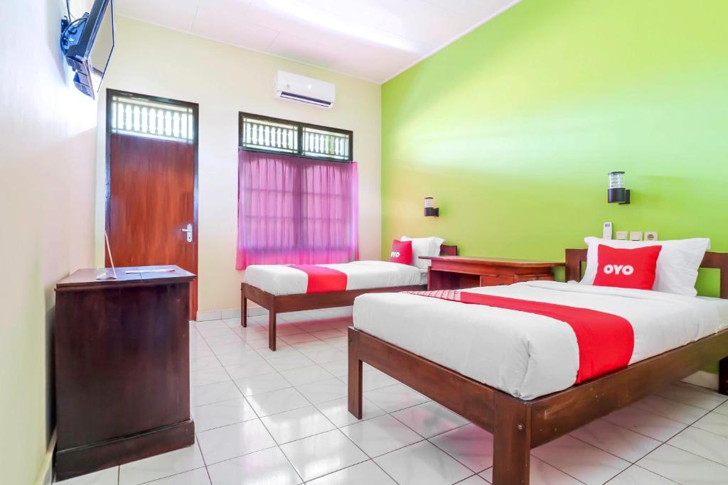 a hotel room with two beds and a tv at OYO 2184 Nan Berlian Inn in Legian