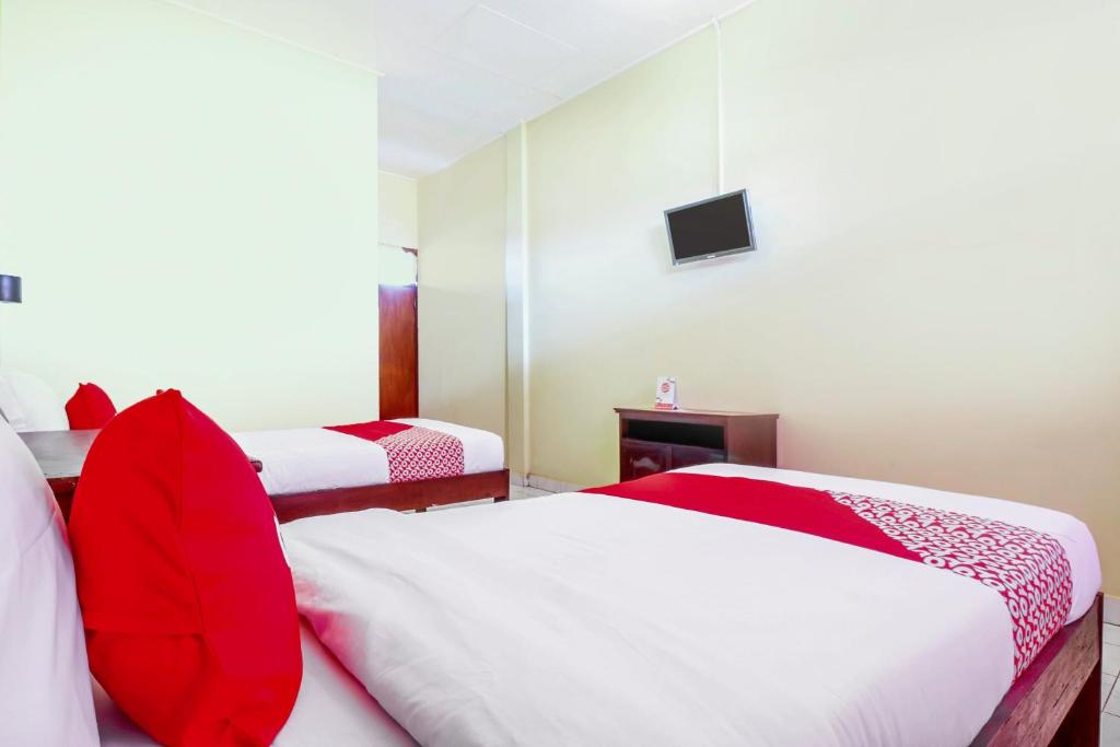 a hotel room with two beds and a tv at OYO 2184 Nan Berlian Inn in Legian