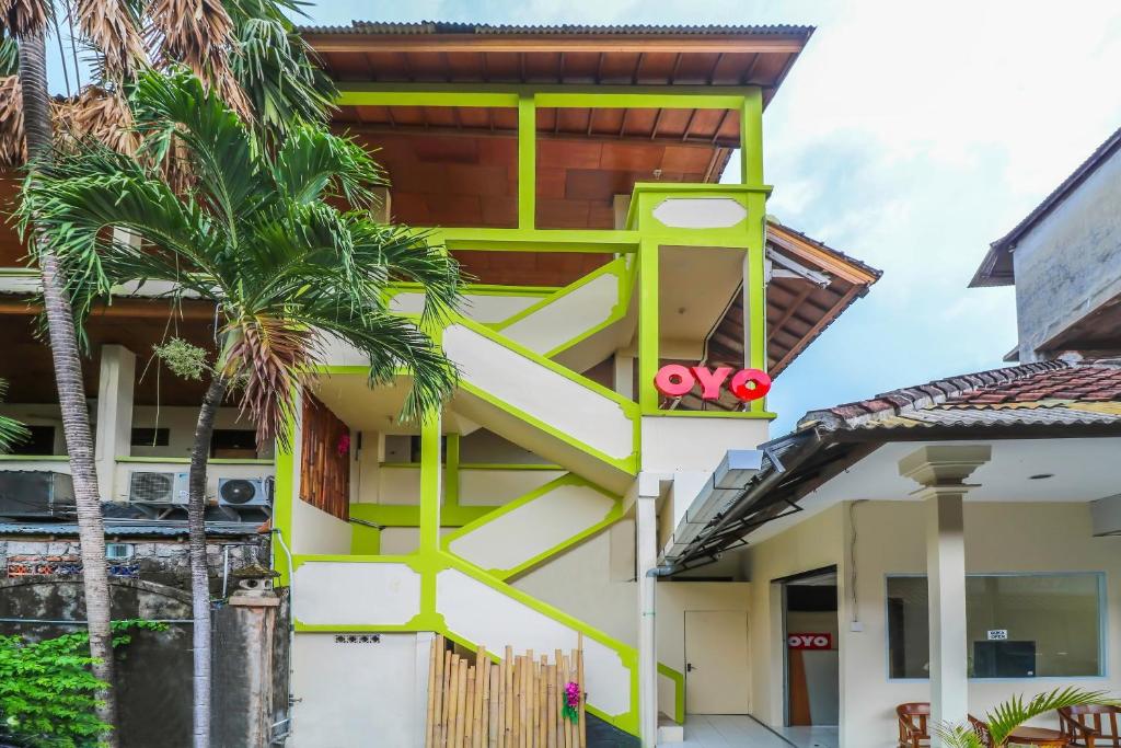 a yellow and white building with a tree at OYO 2184 Nan Berlian Inn in Legian
