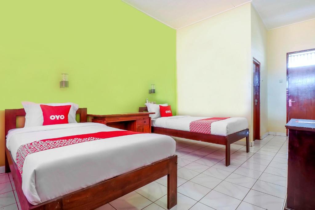 a bedroom with two beds and a bench in it at OYO 2184 Nan Berlian Inn in Legian