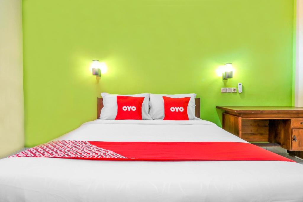 a bedroom with a large bed with two red pillows at OYO 2184 Nan Berlian Inn in Legian