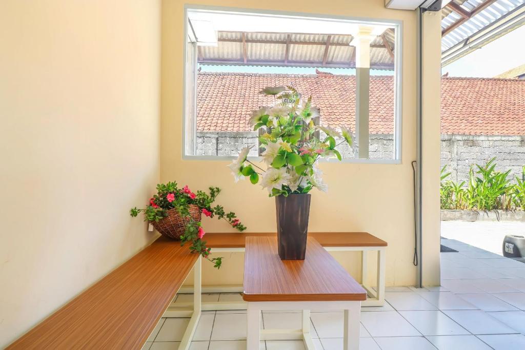 a vase of flowers on a table in a room at OYO 2184 Nan Berlian Inn in Legian
